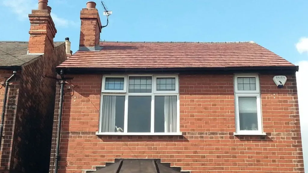Newly fitted pitched roof with red tiles on a red brick residential property.