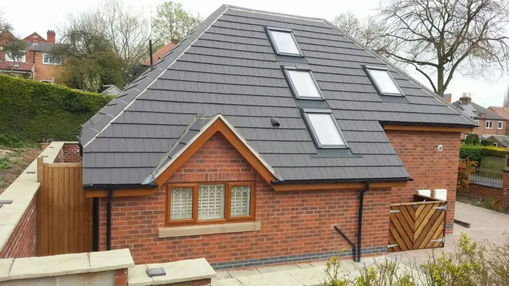 New dark grey pitched roof with multiple Velux windows on a brick building